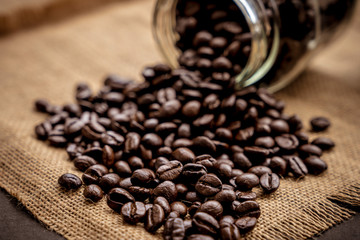 Coffee bean grain in a glass bottle on black table with sack fabric