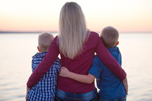 Mother And Two Sons Sitting On The Promenade And Watch The Sunset