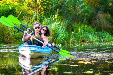 Wall Mural - Family kayaking, mother and child paddling in kayak on river canoe tour, active summer weekend and vacation, sport and fitness concept
