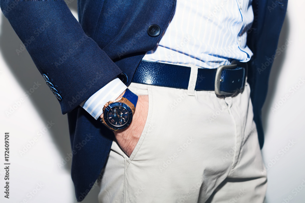Closeup fashion image of luxury watch on wrist of man.body detail of a business man.Man's hand in a white shirt,blue jacket  in a pants pocket closeup. Tonal correction.Man posing in blue suit.
