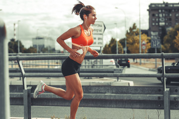 Female runner jogging on the city street by the traffic road.City environment.