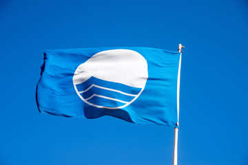 Blue beach flag on the sky background