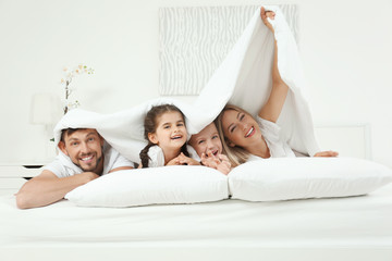 family lying on bed in hotel room