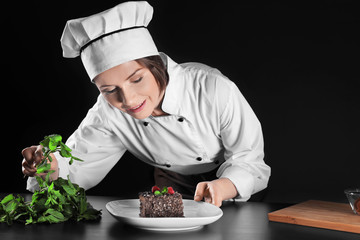 Sticker - Female chef decorating dessert on dark background