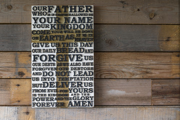 Wooden carved word of the Lord's Prayer on the  shabby wooden  plank  background.