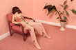 © Ulas and Merve/Stocksy - woman sitting on an armchair in a pink room
