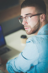 Young man using a phone and working on a laptop. Student texting on the phone.