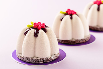 Flower shape mini mousse pastry dessert covered with chocolate velour and decorated with glaze