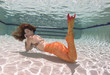 © pipehorse - A mermaid with and orange tail underwater.