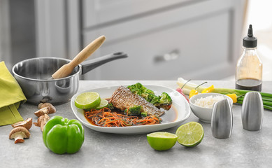 Poster - Plate with delicious fish in sauce and vegetables on table in kitchen