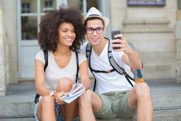 tourist couple taking selfie in city street