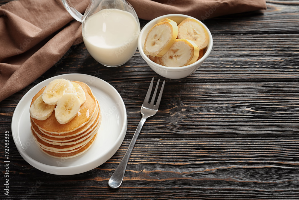Plate with yummy banana pancakes on wooden table