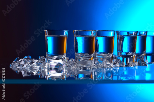 kieliszki-z-nalana-wodka-i-lodem-na-stole-podswietlonym-niebieskim-swiatlem