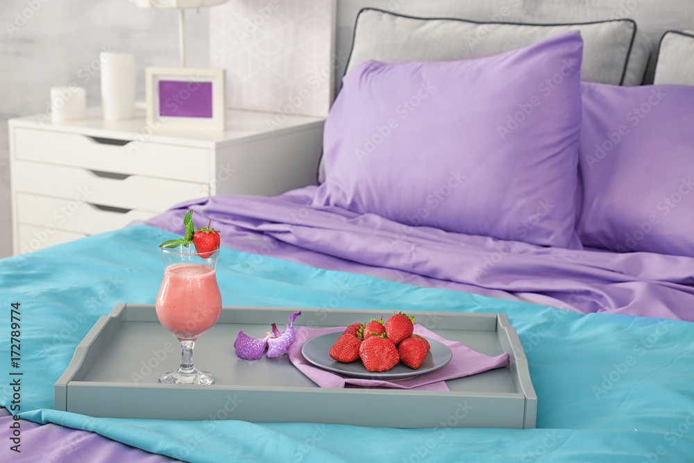 Lilac accent in modern interior. Tray with tasty breakfast on bed