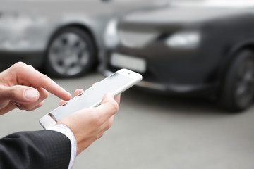 Young man using application on phone for calling taxi outdoors