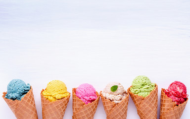 Fototapete - Various of ice cream flavor in cones blueberry ,strawberry ,pistachio ,almond ,orange and cherry setup on white wooden background . Summer and Sweet menu concept.