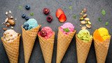 Fototapeta Mapy - Various of ice cream flavor in cones blueberry ,strawberry ,pistachio ,almond ,orange and cherry setup on dark stone background . Summer and Sweet menu concept.