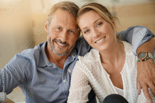 Cuadros en Lienzo Mature couple relaxing at home, looking at camera