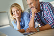 Mature couple connected with laptop at home