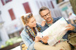 © goodluz - Couple of tourists reading city map and using smartphone