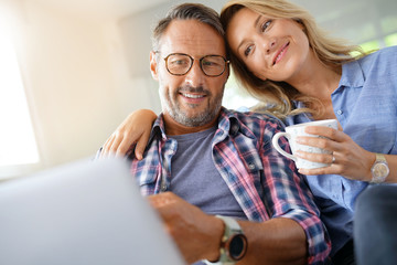 Mature couple connected on internet with laptop