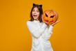 © Drobot Dean - Excited teenage schoolgirl in uniform holding halloween pumpkin