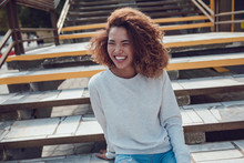 Curly Haired Girl With Freckles In Blank Grey Sweatshirt On The Street. Mock Up.