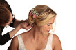Eine Braut wird frisiert von einer Frau mit Zopf und Blumen im Haar