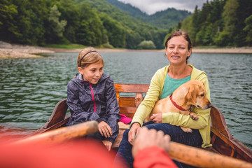 Wall Mural - Family with dog rowing on a mountain lake