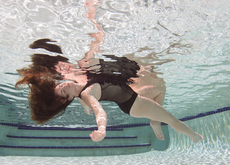 Wall Mural - A woman wearing a black swimsuit underwater.