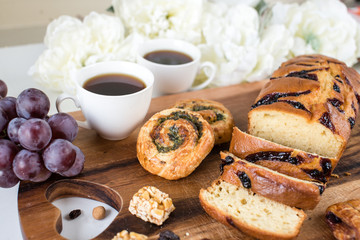 Sliced bread, buns and two cups of coffee on the wooden cutting board