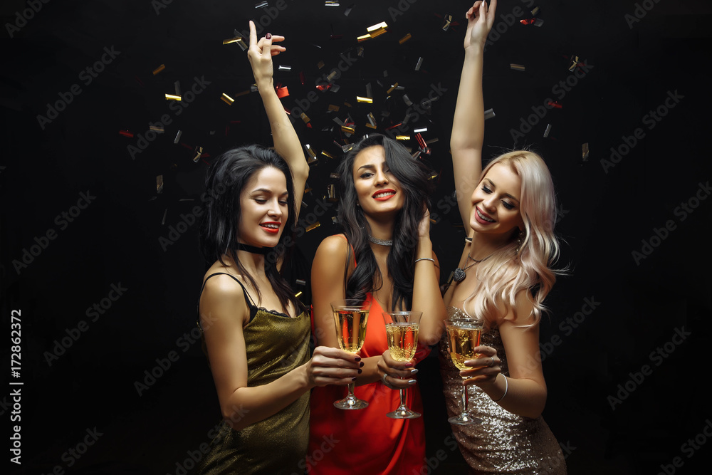 Young attractive women celebrating a party, drinking champagne and dancing - obrazy, fototapety, plakaty 
