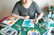 © Jennifer Brister/Stocksy - Artist creating colorful art on messy table