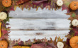Autumn seasonal foliage and decorations for seasonal holidays on white rustic wooden boards