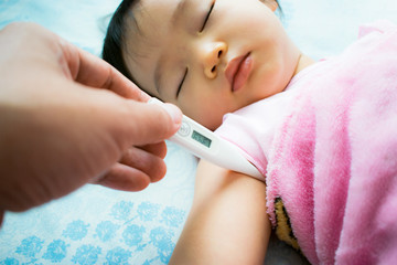 Close-up father's hand holding thermometer. Taking child's temperature.