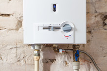 Closeup Of Gas Water Heater On A Brick Wall. Gas Boiler In Boiler Room For Hot Water