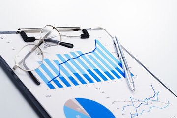 Poster - Growth chart. Reviewing business report. Concept image of analyzing data. Documents and glasses on white reflection background.
