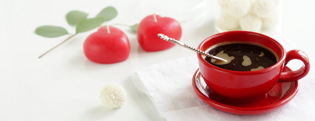 red cup with coffee, two candles-heart and a branch of eucalyptus on a white background. banner