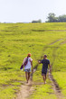 © Westend61 - Back view of couple walking barefoot on a meadow