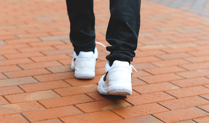 lower part of the male legs in white sneakers