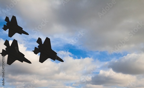 Silhouettes of three F-35 aircraft against the blue sky and white clouds Tableau sur Toile
