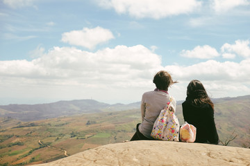 two person, mom and daughter sitting in contemplation of Phu Lom Lo from the terrace above on daytime. 