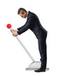 A businessman stands at a large lever with a red round knob and starts to move it.