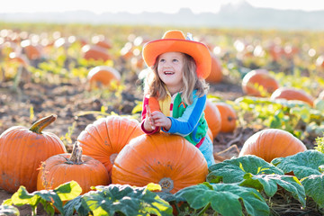 child playing on pumpkin patch