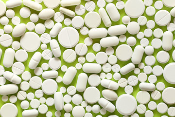 White medicine pills on a green and yellow background