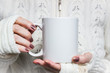 Woman holds white mug in hands. Design Mockup for winter holidays
