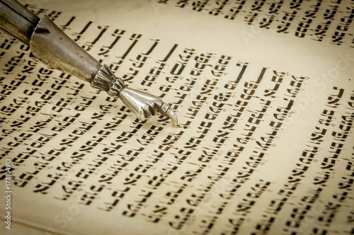 Torah pointer with a hand at the end with one finger extended to help read the text of holy scriptures of Torah. Hebrew letters, Torah chapter, Jewish calendar.