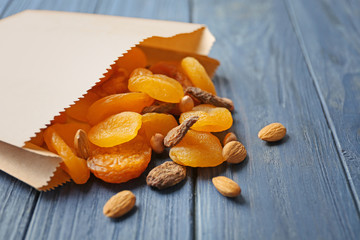 Wall Mural - Paper bag with dried apricots and nuts on wooden background