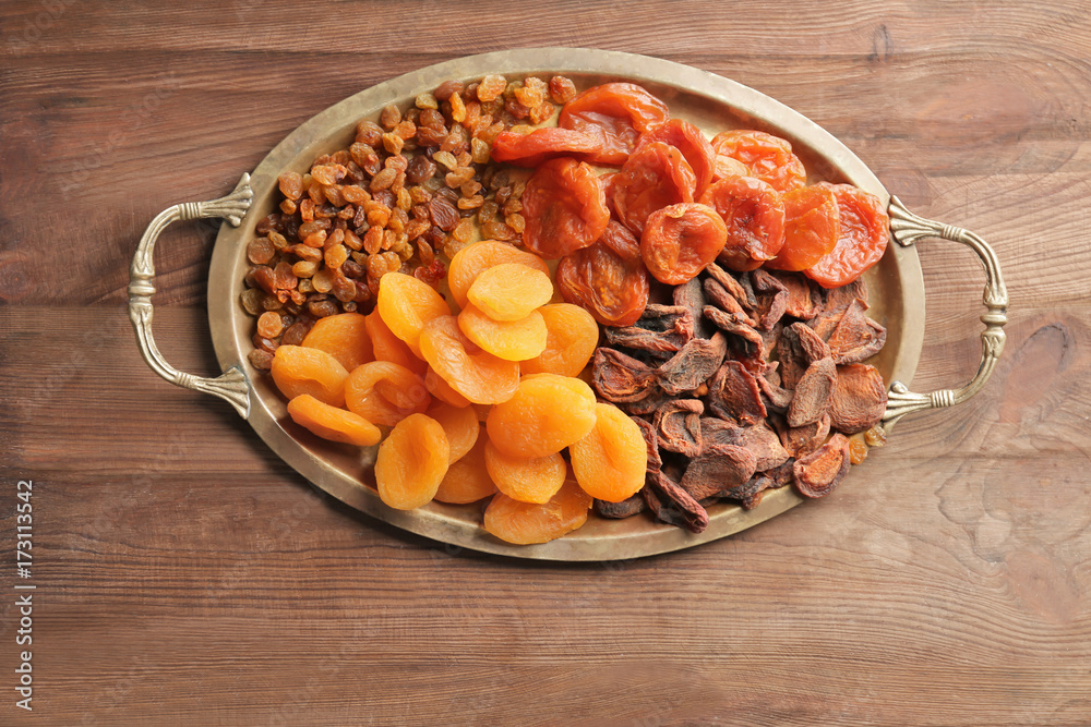 Tray with dried apricots and raisins on wooden background