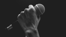 Man Hands Holding Microphone On Stand.